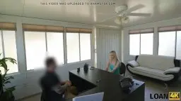 Blonde Anni Angel mit offener Bluse und Jeansshorts steht frech in hellem Loft und zeigt ihren flachen Bauch