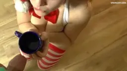 Weihnachtsengel kniet nackt am Boden und trinkt gierig aus blauem Becher mit Pisse