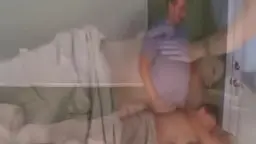 Reife Oma im geblümten Rock steht vor dem Bett, während der junge Mann in blauem Shirt hinter ihr wartet.